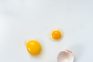 Yolk of broken egg in eggshell decorated with pink sisal nest on the minimalist white background