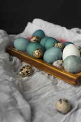 Blue, and white and chicken eggs and quail eggs in wooden retro style box decorated with a pink sisal on vintage style wooden table covered with sackcloth