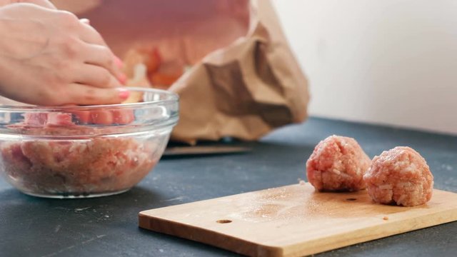 Close-up of a woman's hands making meatballs of minced meat with rice and put it on a wooden board.