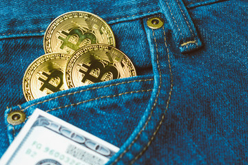 Golden bitcoins and large stack of money in the pocket of old vintage indigo stonewashed jeans. Concept of choice between crypto currency and physical money. Modern trendy color