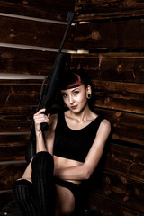 Fototapeta na wymiar Beautiful sexy redhead holding pneumatic weapon on a wooden background