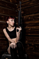Fototapeta na wymiar Beautiful sexy redhead holding pneumatic weapon on a wooden background