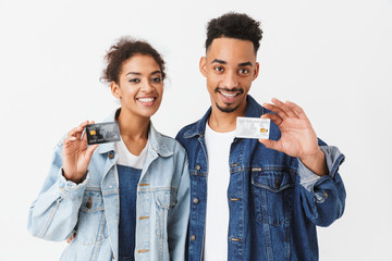 Smiling african couple in denim shirts holding credit cards - Powered by Adobe
