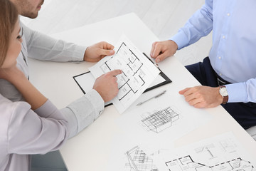 Real estate agent showing plan of apartment to clients in office
