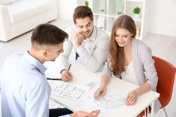 Real estate agent showing plan of apartment to clients in office