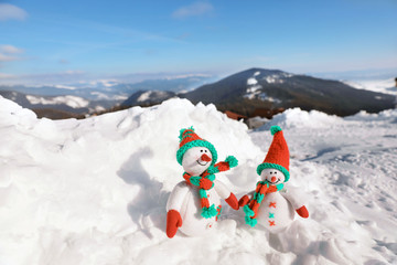 Two toy snowmen at mountain resort on sunny frosty day. Winter vacation