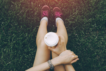 Sport young asian woman sitting on grass, drinking coffee. Resting Runner. Vintage filter.