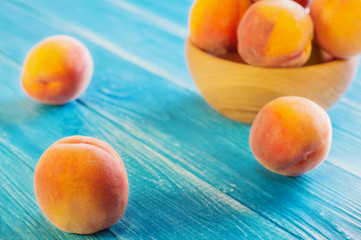 Fresh ripe peaches in a wooden bowl on a blue wooden background.