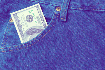 Large stack of money in the pocket of old vintage indigo stonewashed jeans. Modern ultraviolet style. Close up