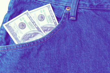 Large stack of money in the pocket of old vintage indigo stonewashed jeans. Modern ultraviolet style. Close up