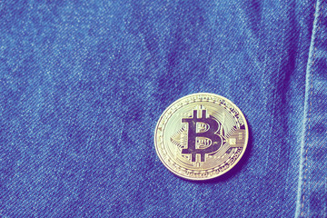 Golden bitcoins in the pocket of old vintage indigo stonewashed jeans. Concept of bitcoin - a...