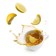 Obraz na płótnie Canvas lemon slices falling into cup of tea and splashing