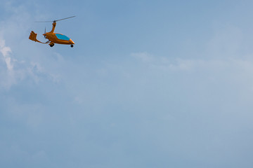 Small and Light Orange Helicopter against Blue Sky