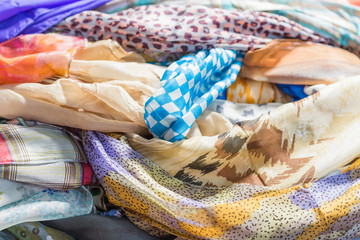 Background with scarves of different colors. Closeup, selective focus.