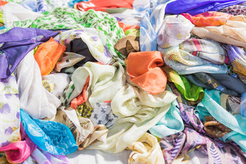 Background with scarves of different colors. Closeup, selective focus.