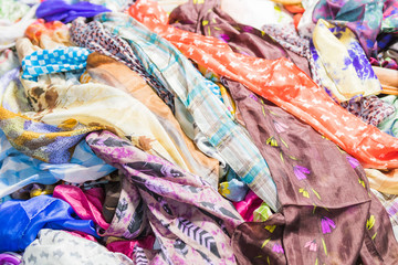 Background with scarves of different colors. Closeup, selective focus.