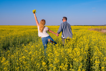 Fototapeta premium Joyful couple with open arms is walking through the field
