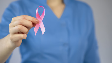 Doctor showing pink ribbon closeup, breast anticancer campaign, examination