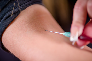 Closeup of nurse's hands taking a blood sample with a syringe
