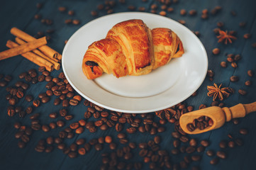 black, strong coffee with croissants in a white dish sprinkled with cinnamon and anise on a blue...