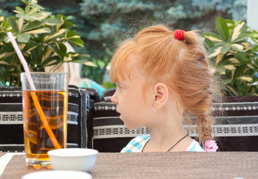 Beautiful red-haired little girl in a cafe.