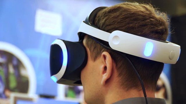 Close up young man using VR headset playing virtual reality game turning head 4k