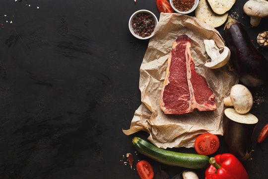 Raw t-bone steak with vegetables on parchment
