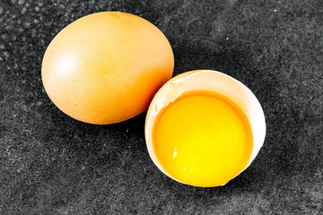Fresh egg broken in its shell with a whole egg on a vintage background