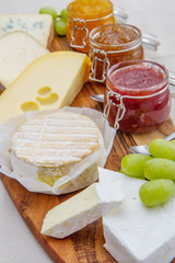 wooden cutting board with cheese and jams