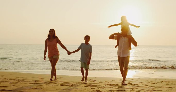 Happy young family on the beach at sunset