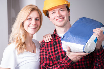 Paar fröhlich bei Renovierungsarbeiten auf einer Baustelle 