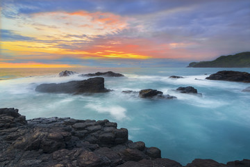 Obraz premium Beautiful Sunset at Menganti beach of Indonesia, Sunset and rocks on the beach