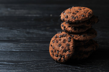 oatmeal cookies with chocolate on a dark wooden background