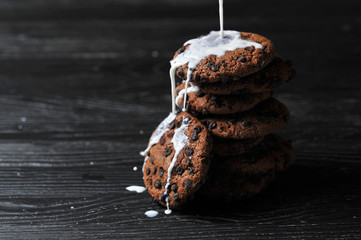 oatmeal cookies with chocolate and milk on a dark wooden background
