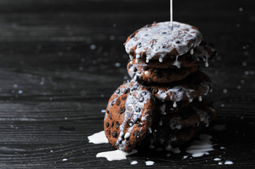 oatmeal cookies with chocolate and milk on a dark wooden background