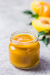 Golden plum sauce in ceramic bowl glass jar and fresh golden plums on concrete background. Selective focus, space for text. 