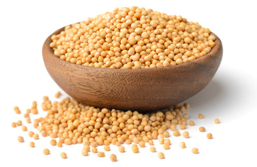 yellow mustard seeds in the wooden plate, isolated on white