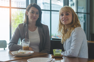 portrait of two attractive young women meeting in coffee shop.