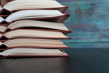 Open book hardback on Stack books on wooden background. Back to school with copy space.