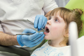 Dentist examining little girl's teeth in clinic. Dental problem.