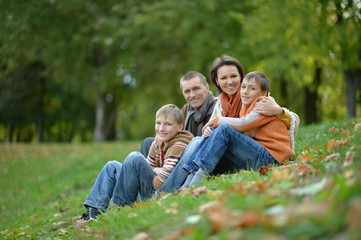 Fototapeta premium Happy smiling family in autumn forest sitting 