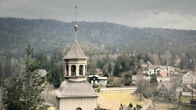 Old and stained Baroque church. Yellow pebbled and flaked facade. Church small tower with bell and cross. Sunny weather. Static day stabilized v-log shot.