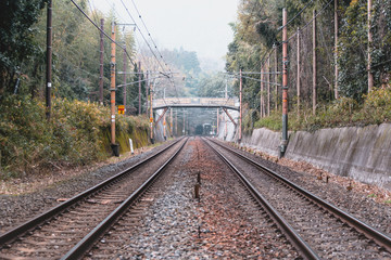 Train track surrounded with trees and mountains in Arashiyama, Kyoto, Japan