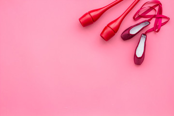 Beauty sport for girls concept. Maces for rhythmic gymnastics and ballet shoes on pink background top view copy space