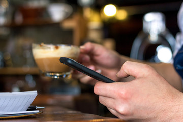 Fototapeta na wymiar Human hand holding mobile phone blank screen touching in coffee shop