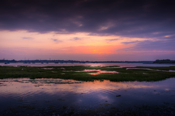 Fototapeta na wymiar Beautiful warm sunset reflecting on calm water at Holes Bay in Poole, Dorset
