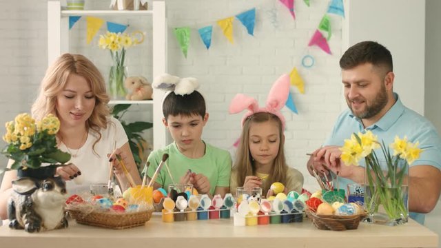 Portrait of a happy family with two children drawing Easter eggs