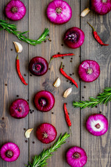 Red onion as seasoning. Onion near chili peper, rosemary, black peper, garlic on dark wooden background top view