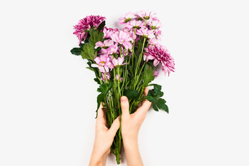 Flatlay with woman's hand holding bouquet of pink and violet flowers, spring of summer concept. top view