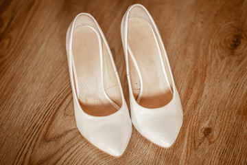 Fototapeta premium white women's wedding shoes on wooden floor